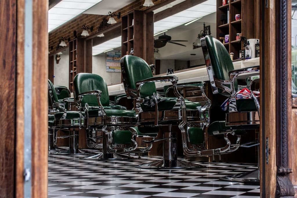 Charming vintage barber shop with classic green chairs and checkered floor tiles.